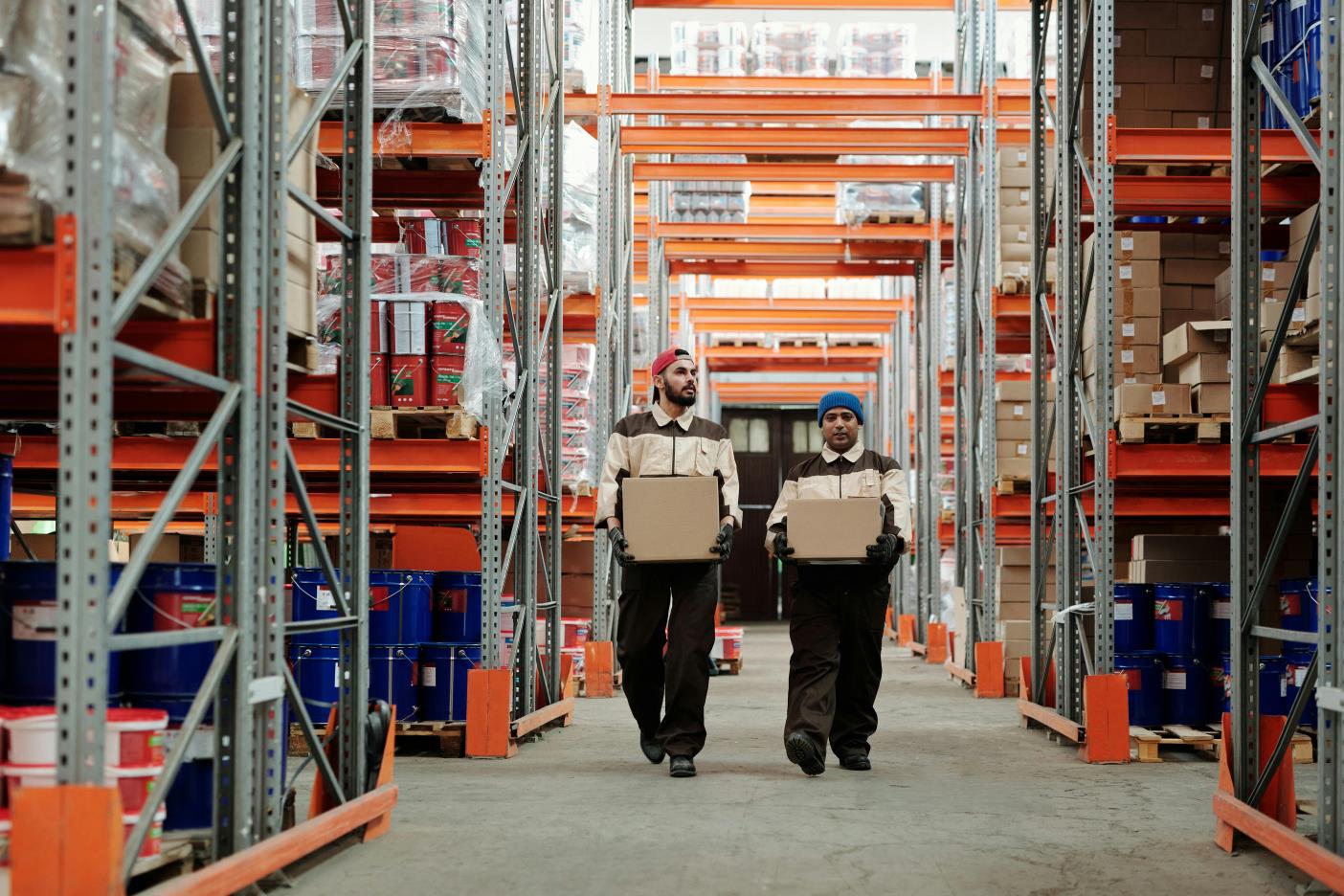 Two people walking through a warehouse filled with boxes, showcasing Apexel 1 year warranty.