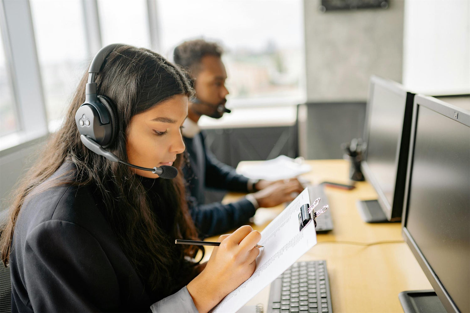 A professional woman in an office wearing headphones and a headset, providing exceptional customer service at Apexel 24X7.
