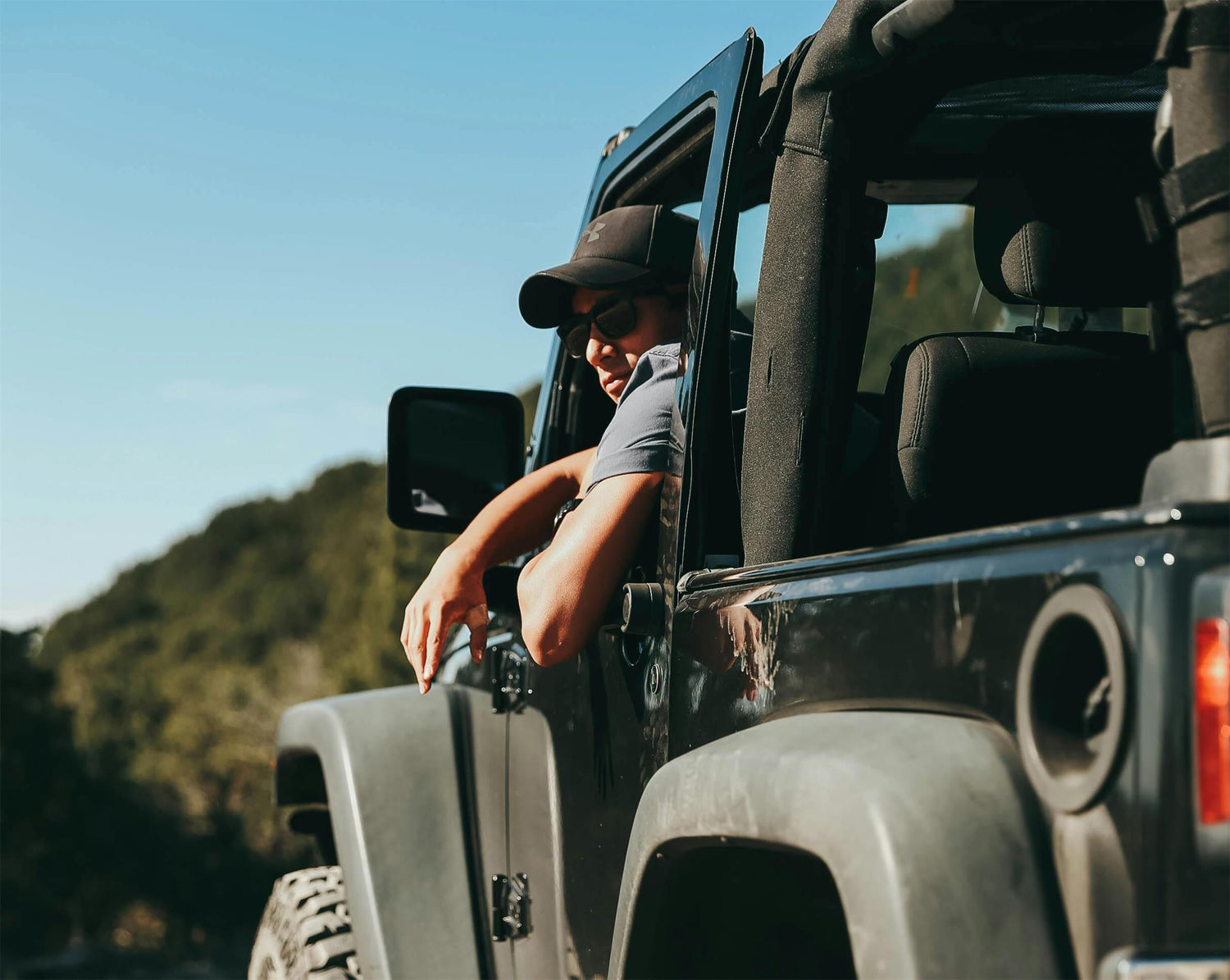 Join the adventure! A cool guy in a hat and sunglasses takes the wheel of a jeep. Discover the great outdoors with Apexel founder and outdoor life lover.
